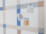 Felt Right wall art design using shades of blue, grey, and cream to created a plaid pattern. Pictures pinned on it.