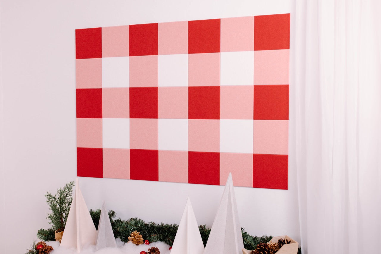 Red and pink checkered backdrop with white decorative elements and greenery.