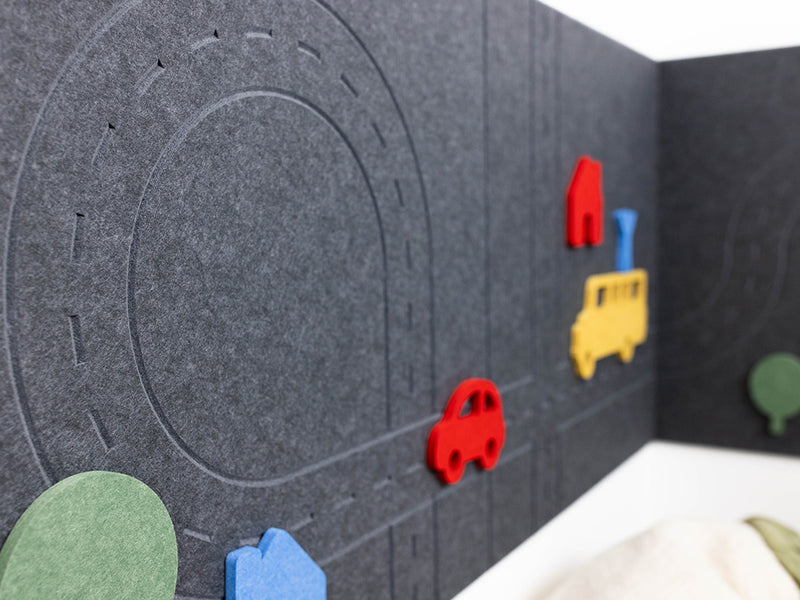 Children's play area with felt road and toy vehicles on a grey surface