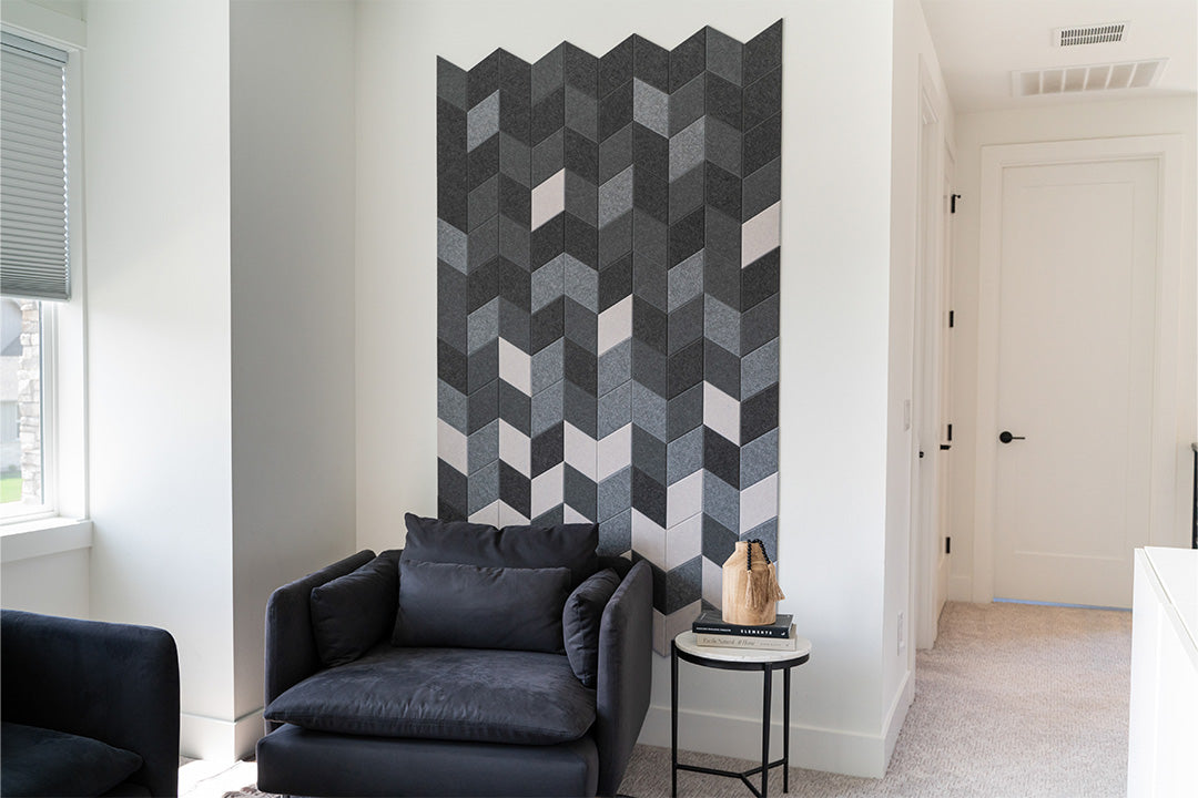 A Felt Right wall art design in shades of grey diamond felt tiles on a white wall in front of a loveseat and a side table.