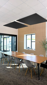 Two black square acoustic panels suspended from white grid ceiling above wooden conference table.