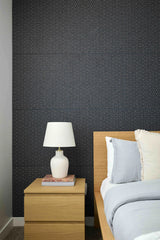 Bedroom with dark patterned wall tiles, wooden nightstand, and bed with pillows.