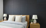Modern bedroom with a bed, nightstands, and lamps against a dark textured wall.