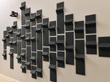 Black three-dimensional tiles arranged in a staggered wall installation pattern with varying depths and projections.