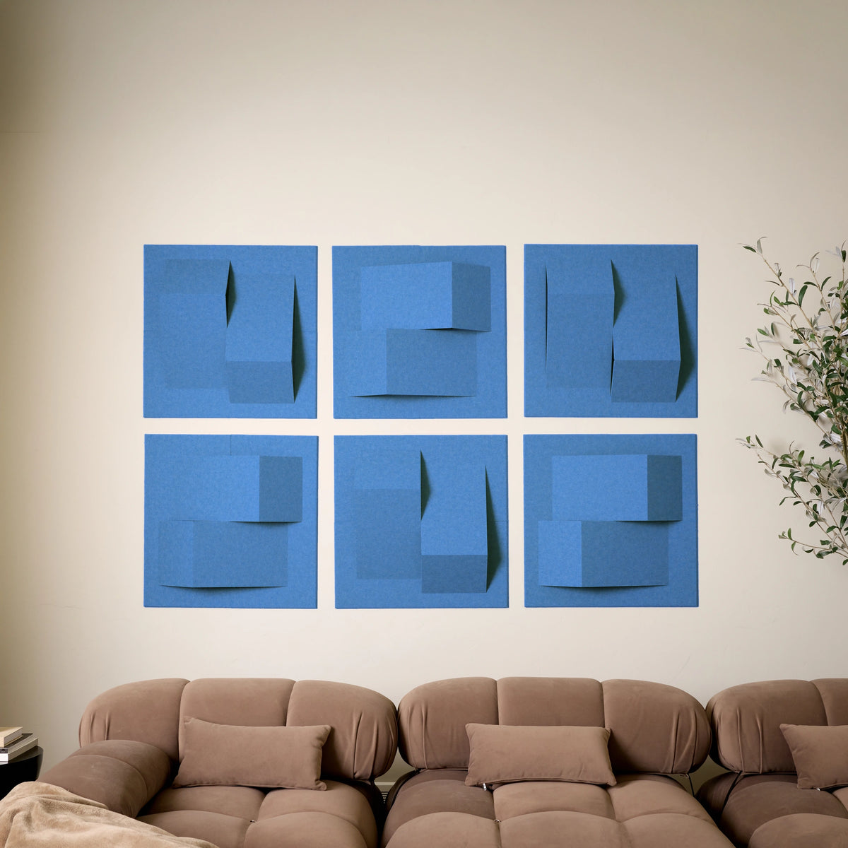 Bright blue felt tiles with a 3D design to help with the acoustics on a wall above a couch