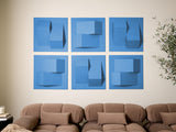 Six blue square tiles with layered geometric shapes and varying shades of blue arranged in a 2x3 grid on a wall.
