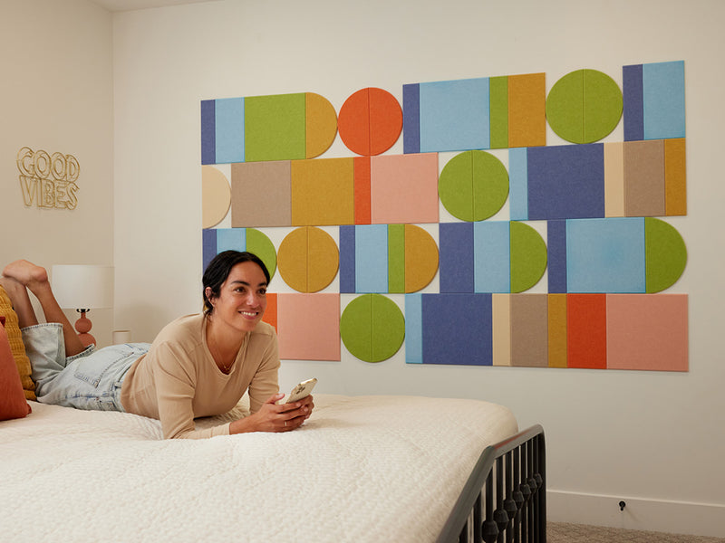 Woman lying on a bed with colorful geometric wall art in the background