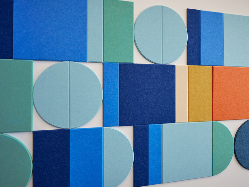 A Felt Right wall art design using squares, rectangles, and circle felt tiles in shades of blue, orange, and yellow creating a geometric wall pattern