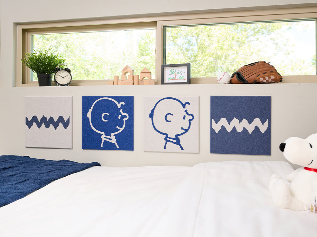 Bedroom with Snoopy plush toy and decorative pillows on a bed, featuring Charlie Brown illustrations on the wall.