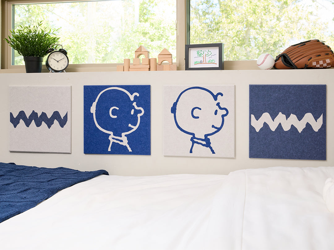 Bedroom with Snoopy plush toy and decorative pillows on a bed, featuring Charlie Brown illustrations on the wall.