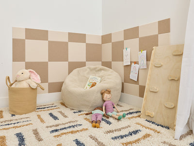 Children's playroom with checkered wall, bean bag, toys, and a basket.