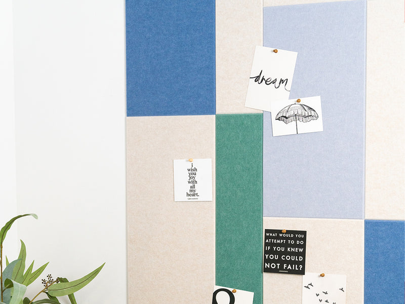 A Felt Right wall art design used as a pinnable board in shades of cream, green, and blue on a white wall. 
