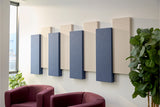 Acoustic panels on a wall with a modern interior design featuring a sofa and plants.
