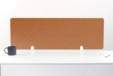 Tan cork desk divider with white mounting brackets displayed on white desk surface.