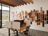 Modern office setup with wooden desk, computer monitors, and a decorative wall art piece.