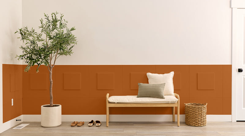 Entryway with wainscoting, a bench, plant, and shoes on a wooden floor.