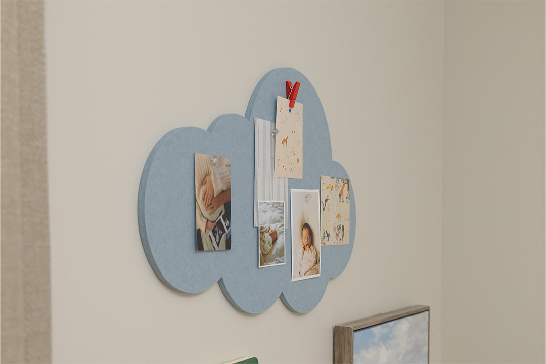 Cloud-shaped magnetic board on a wall with photos and notes attached.