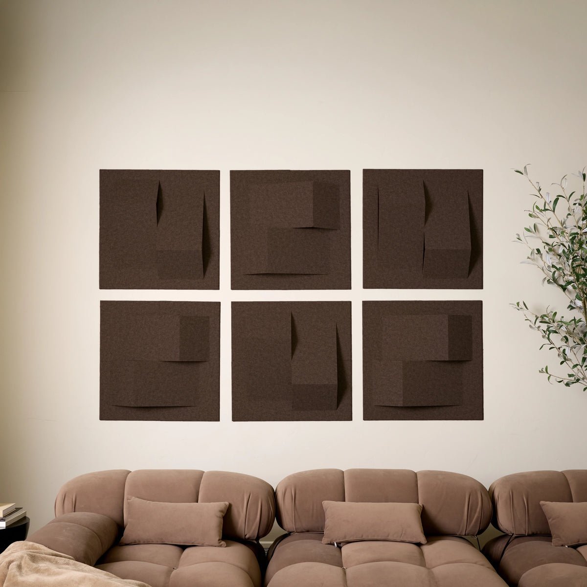 Dark brown acoustic felt tiles with points of dimension on a white wall above a couch