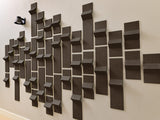 Dark gray three-dimensional tiles arranged in an abstract wall pattern with varying depths and angles.