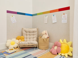 Children's playroom with a colorful rug, toys, and a wall with a rainbow stripe.
