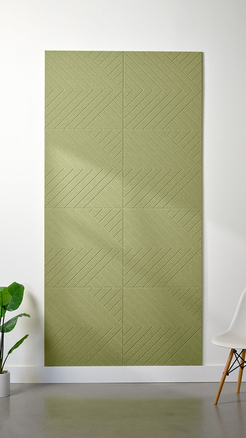 Aloe green Felt Right 4’ x 8’ PET felt panel with geometric lines engraved into the material against a white wall. A plant and chair are in the foreground.