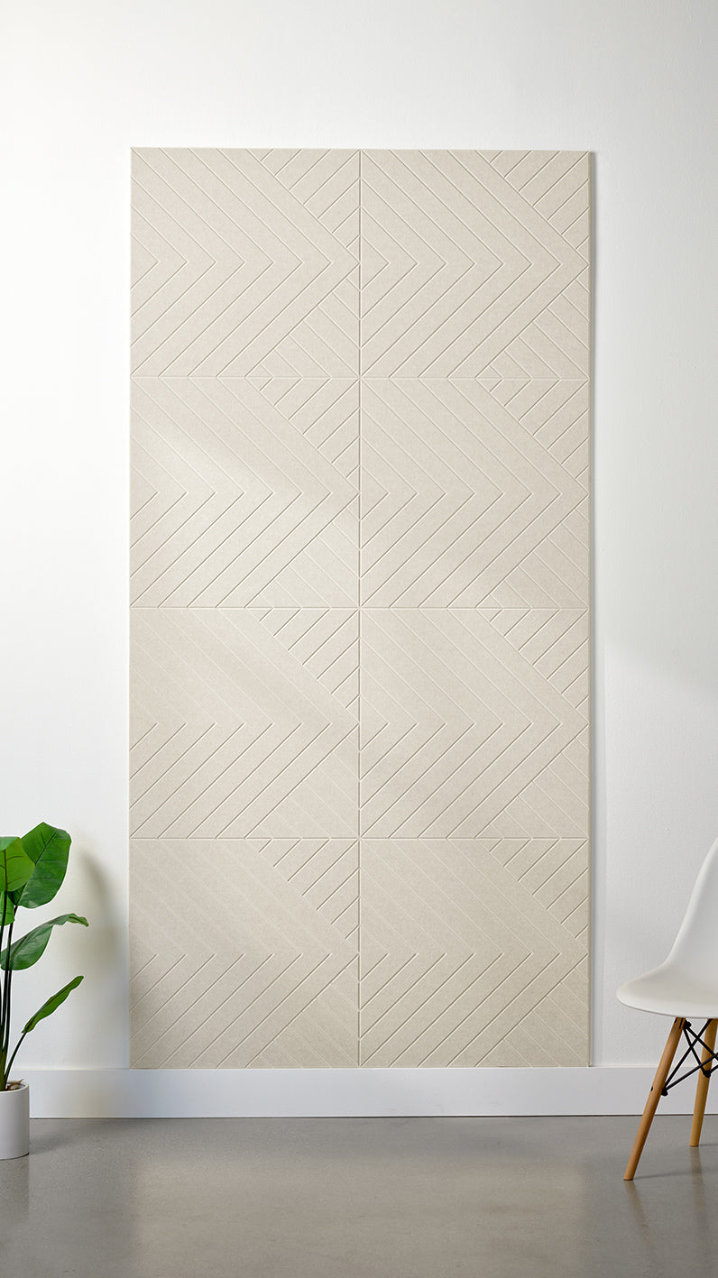 Ivory Felt Right 4’ x 8’ PET felt panel with geometric lines engraved into the material against a white wall. A plant and chair are in the foreground.