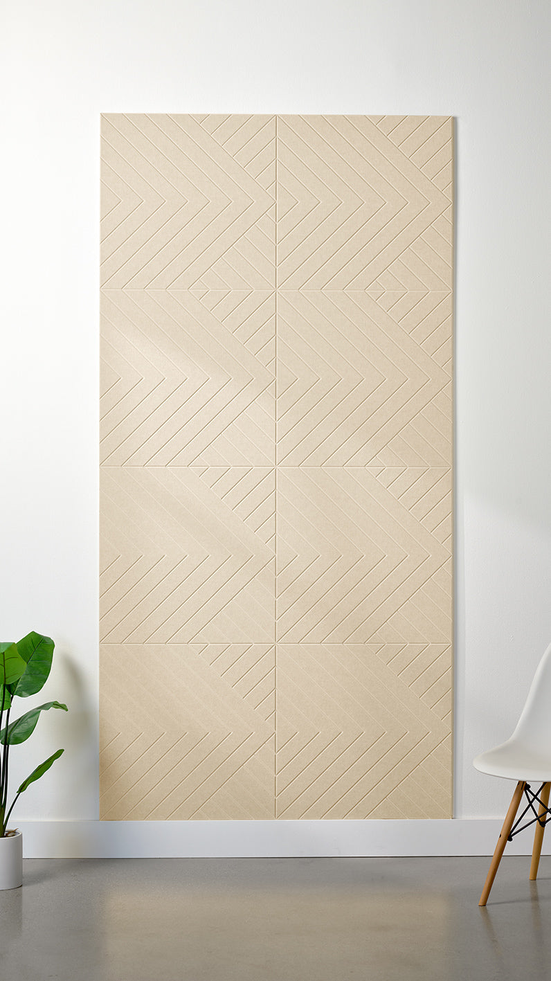 Beige Felt Right 4’ x 8’ PET felt panel with geometric lines engraved into the material against a white wall. A plant and chair are in the foreground.