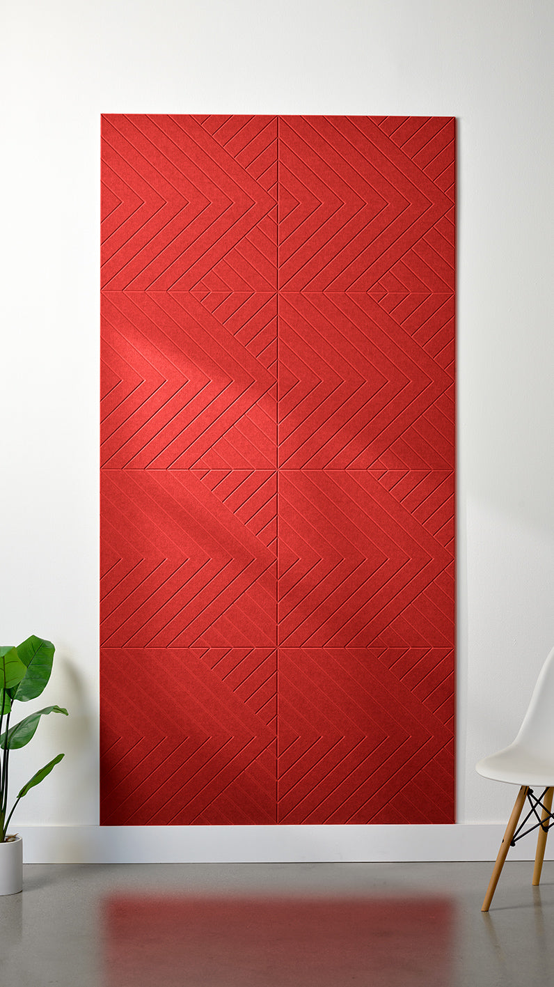 Red Felt Right 4’ x 8’ PET felt panel with geometric lines engraved into the material against a white wall. A plant and chair are in the foreground.