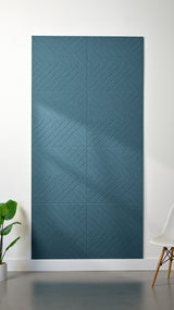 Blue Felt Right 4’ x 8’ PET felt panel with geometric lines engraved into the material against a white wall. A plant and chair are in the foreground.