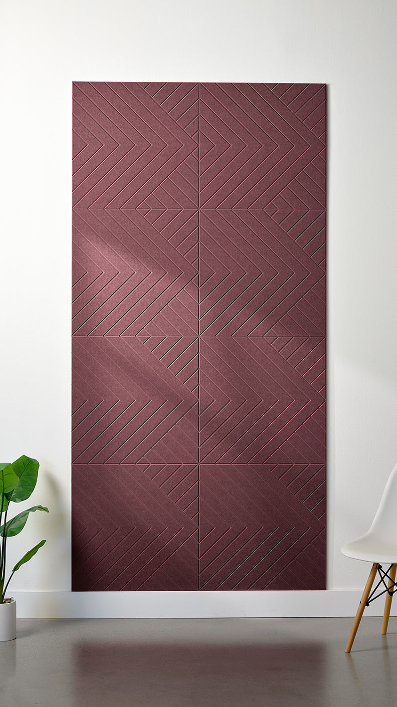 Maroon Felt Right 4’ x 8’ PET felt panel with geometric lines engraved into the material against a white wall. A plant and chair are in the foreground.