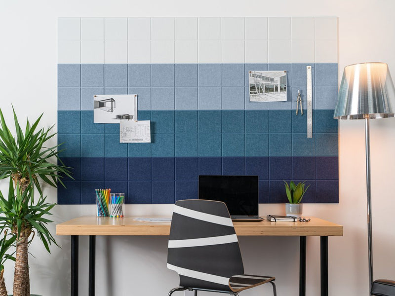 Felt Right Wall art in shades of blue that is pin-able in an office or bedroom above a desk with a plant and a lamp on the side