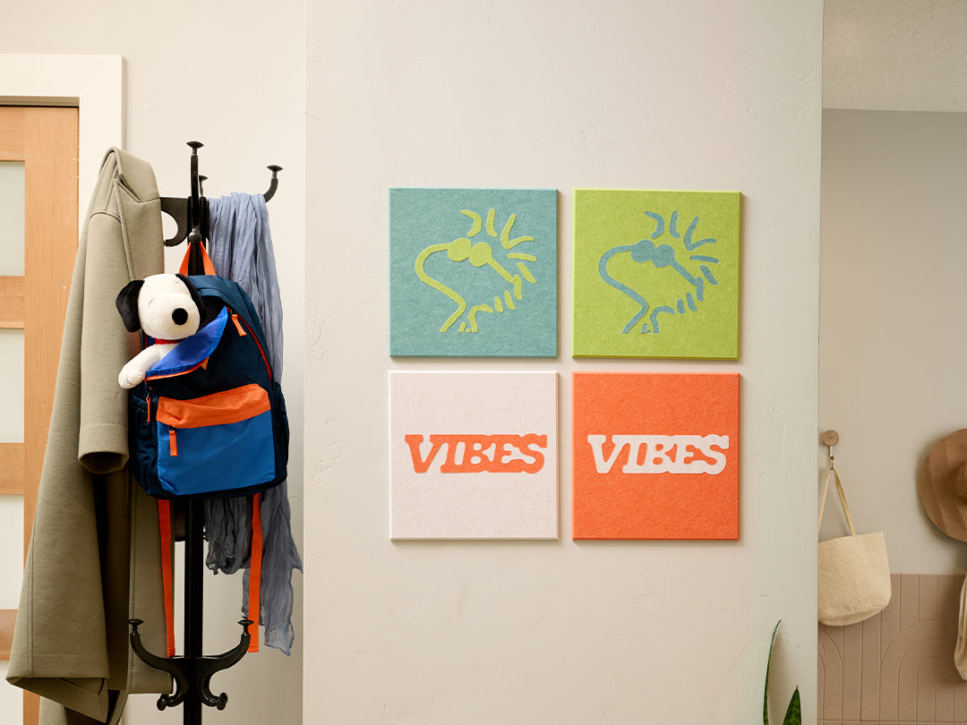 Wall with hooks, coats, backpacks, and colorful Woodstock Peanuts wall art in a room setting.