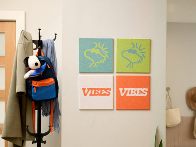 Wall with hooks, coats, backpacks, and colorful Woodstock Peanuts wall art in a room setting.