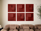 Six burgundy dimensional tiles with geometric cutouts and shadows arranged in grid formation on wall above sofa.