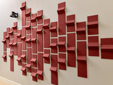 Red dimensional tiles arranged in a wave pattern on a white wall with varied depths and angles.