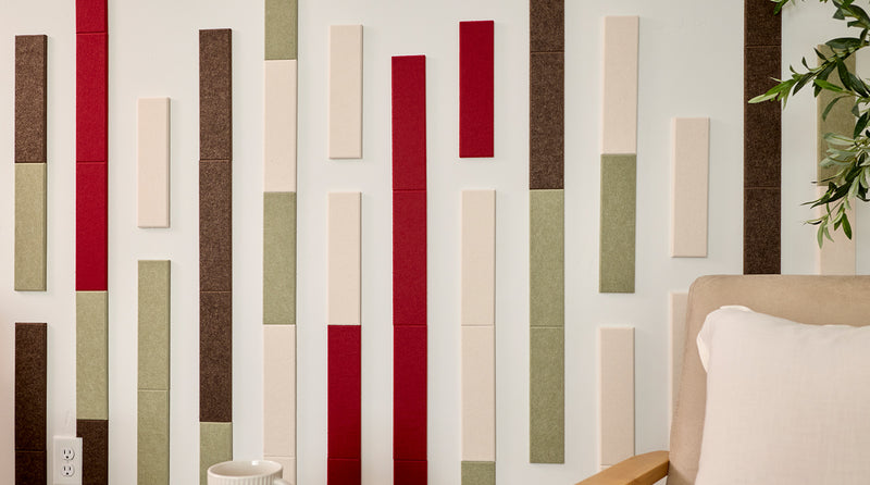 Two beige armchairs with wooden frames in front of a wall with vertical acoustic panels