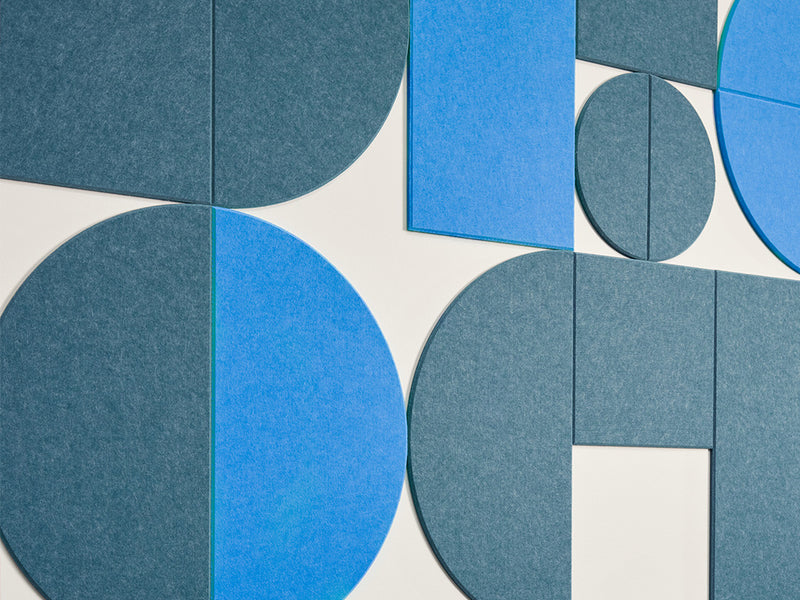 A Felt Right wall art design in shades of blue using circles and squares to create geometric design on a white wall.