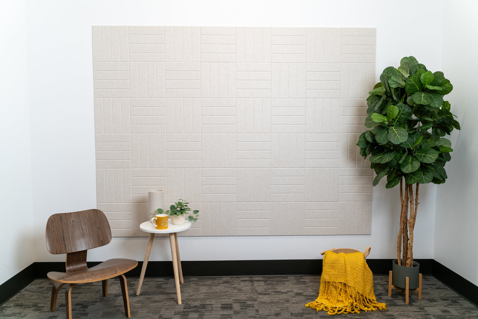 A Felt Right wall design in a cream shade next to a side table and chair and a house plant.