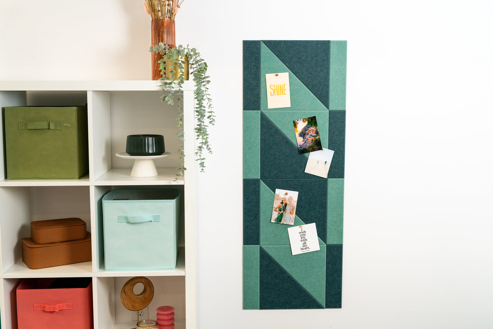 A Felt Right Design wall-mounted, geometric patterned display board in green and white, with items such as a picture frame and notes hung on it.