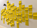 Yellow dimensional tiles with varying depths arranged in an abstract wall pattern against white background.