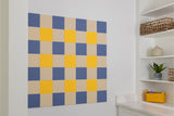 Blue, yellow, and beige gingham pattern pinboard mounted on white wall.
