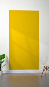 Bright yellow felt sheet displayed on white wall in interior setting.