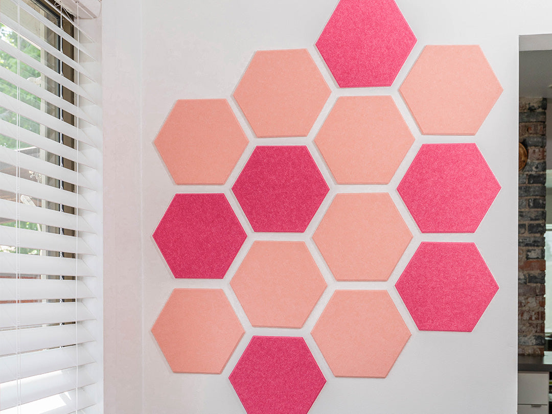 Hexagonal pink and coral acoustic panels on a white wall.
