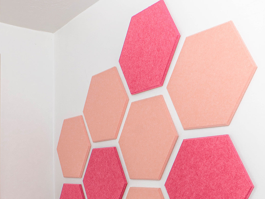 Hexagonal pink and coral acoustic panels on a white wall