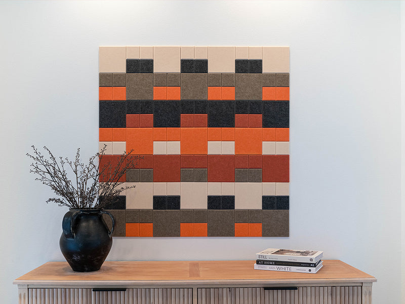 Colorful geometric wall art above a wooden cabinet with a vase and books.