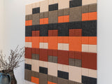 Colorful square tile wall art on a white wall with a vase of dried plants.