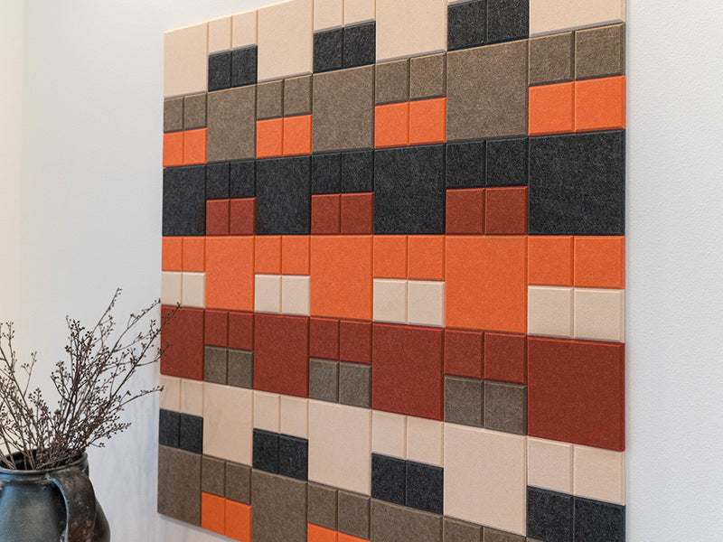 Colorful square tile wall art on a white wall with a vase of dried plants.