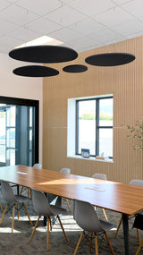 Four black flat cloud-shaped acoustic baffles suspended from ceiling in commercial office space above conference table.