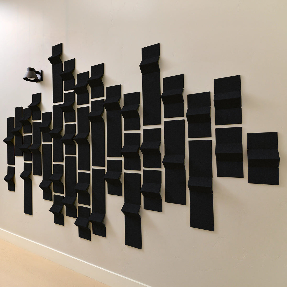 Black acoustic felt tiles on a wall with peaks