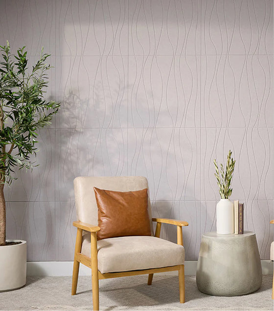 Beige armchair with a brown leather pillow in a room with textured wall and small table.